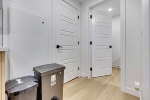 Un couloir avec des portes blanches et une poubelle.