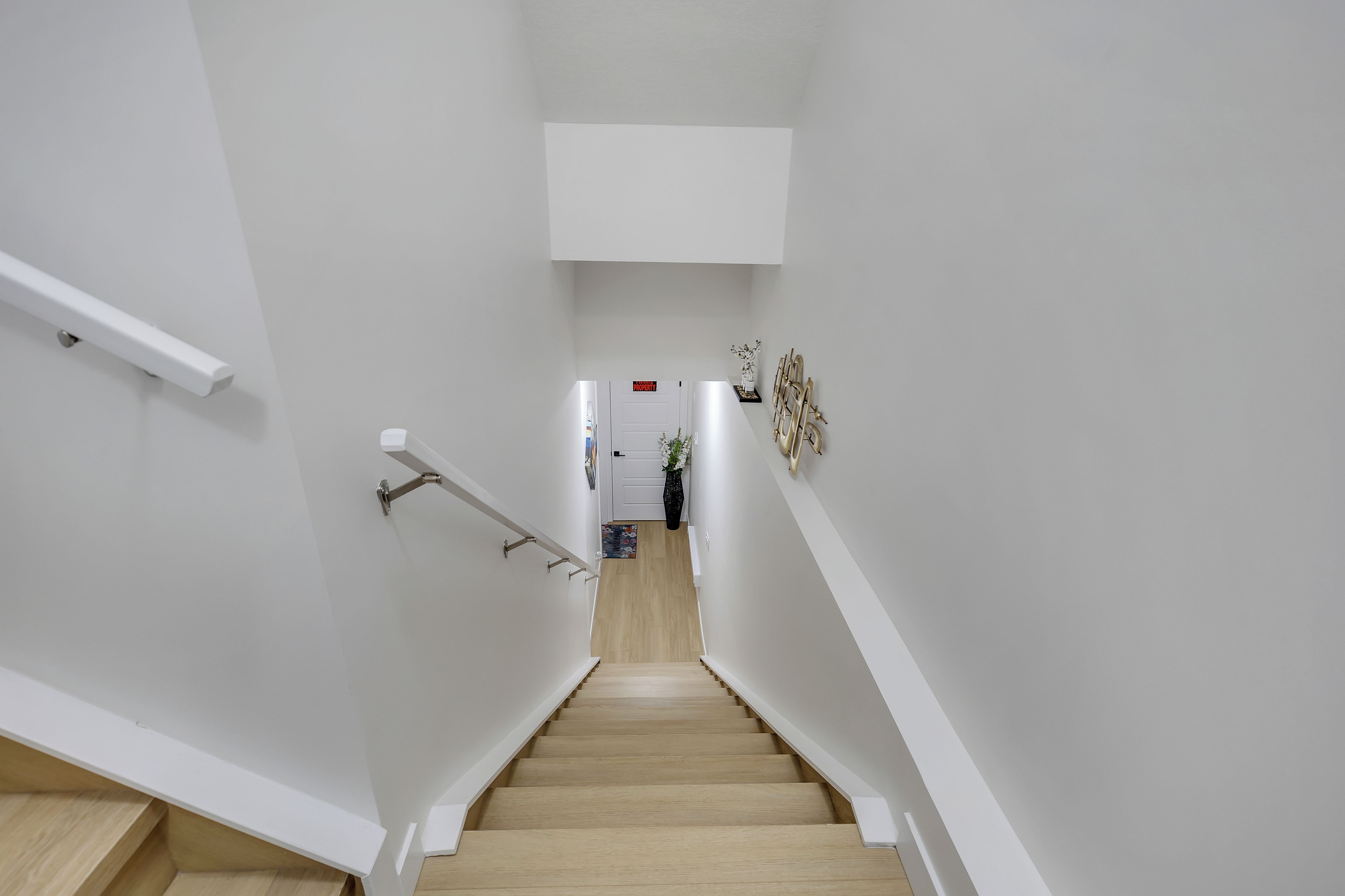 A staircase with white walls and wooden steps leading to a landing.