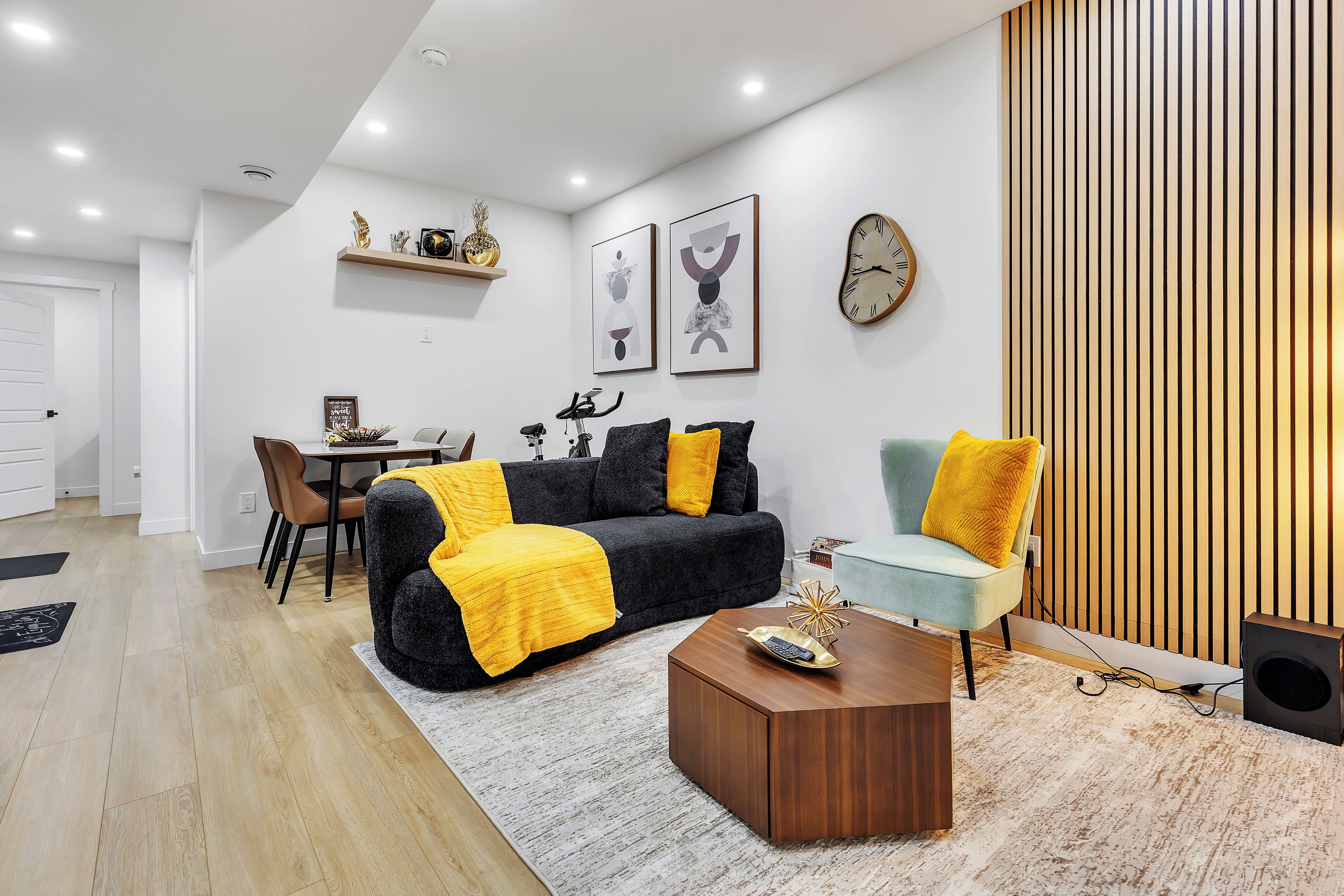 A modern living room with a sofa, coffee table, and a dining area with chairs and a table.