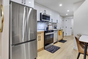 Una cocina moderna con electrodomésticos de acero inoxidable, armarios de madera y un comedor con mesa y sillas.