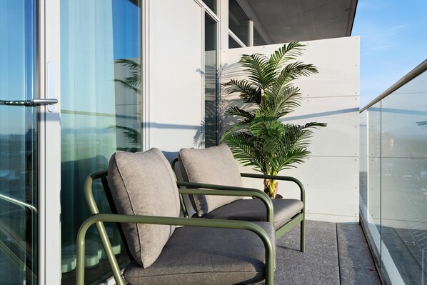 A balcony with a modern chair and a potted plant.