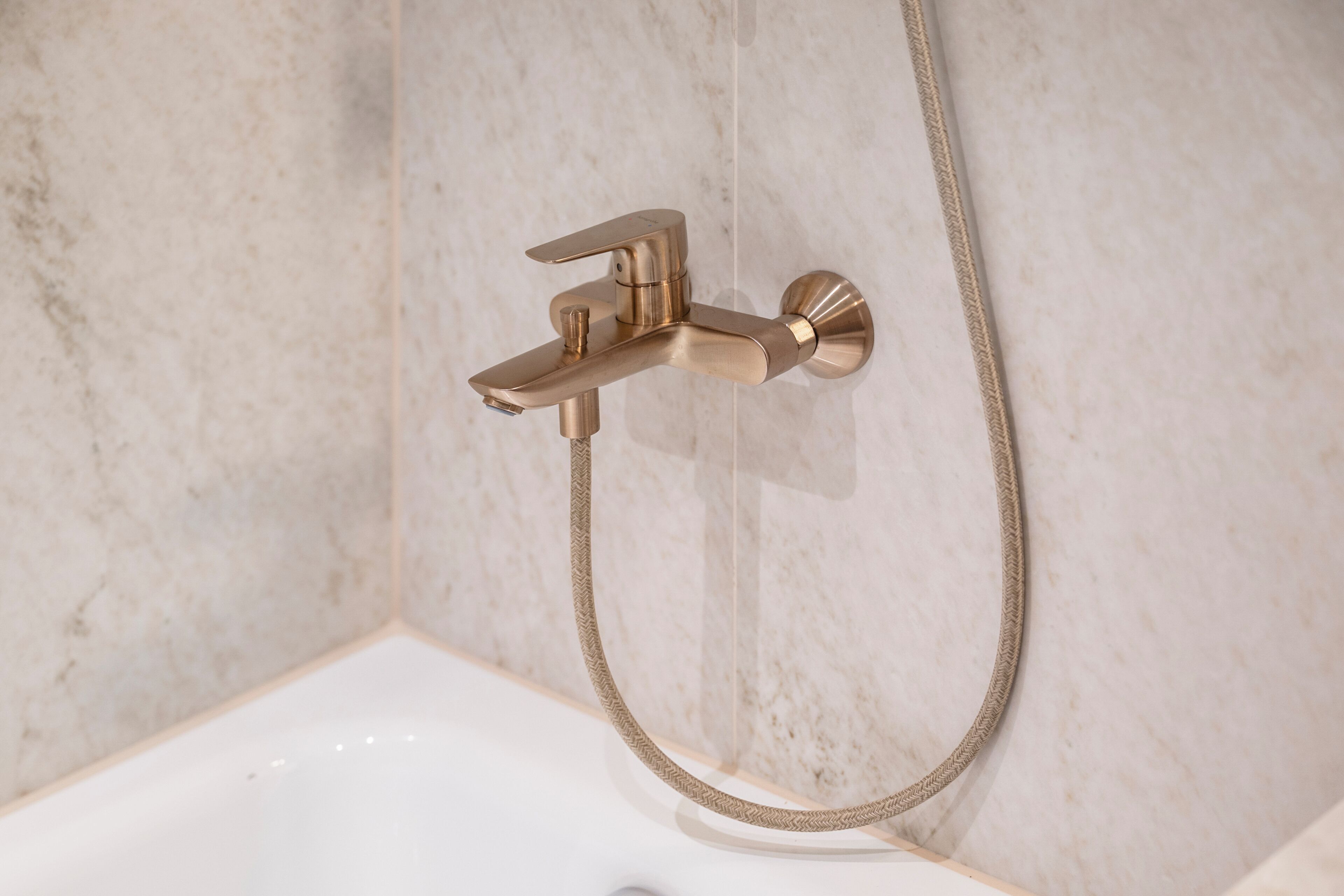 Un baño con grifo y manguera de ducha empotrados en la pared.