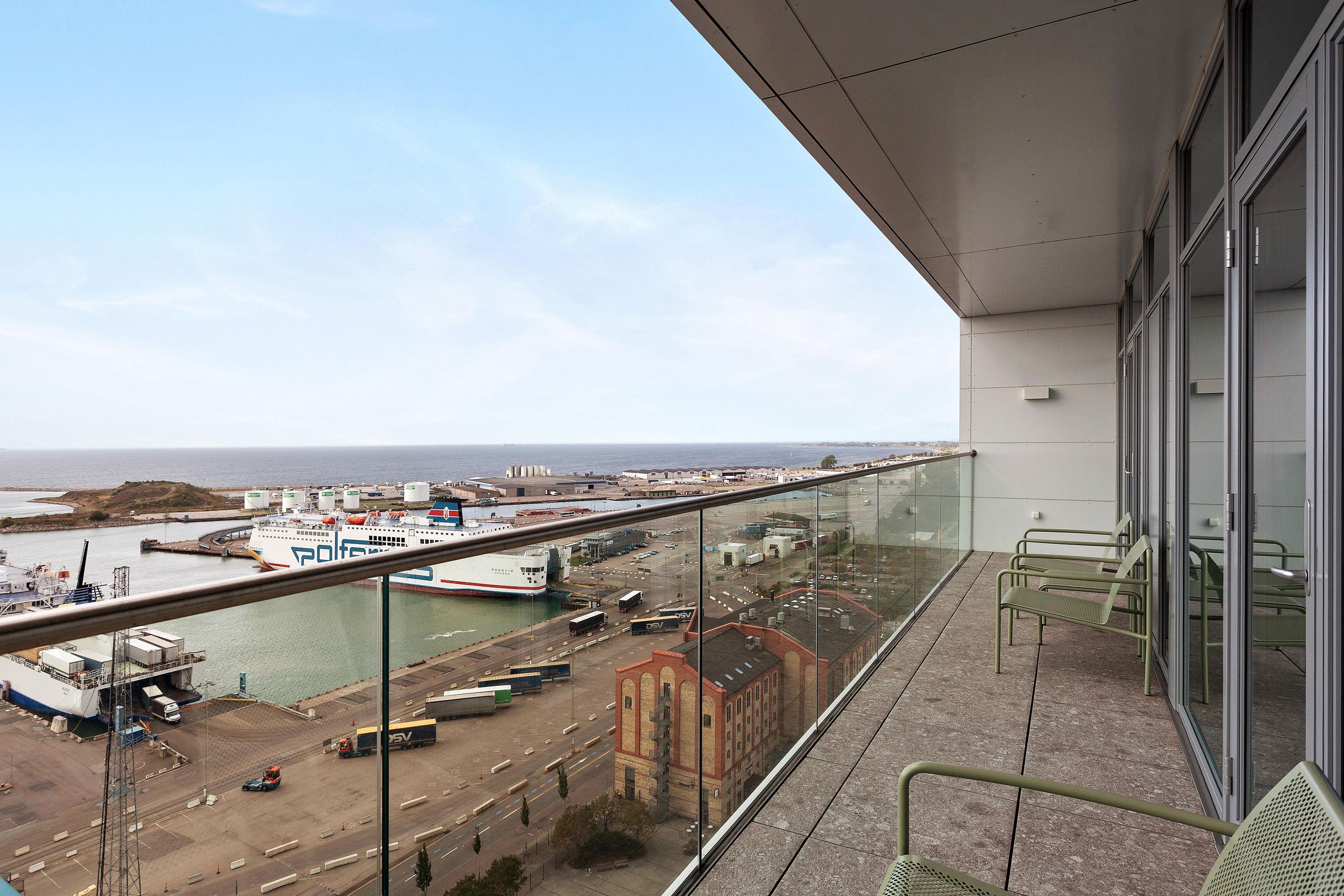 A balcony with a view of a port and industrial area.