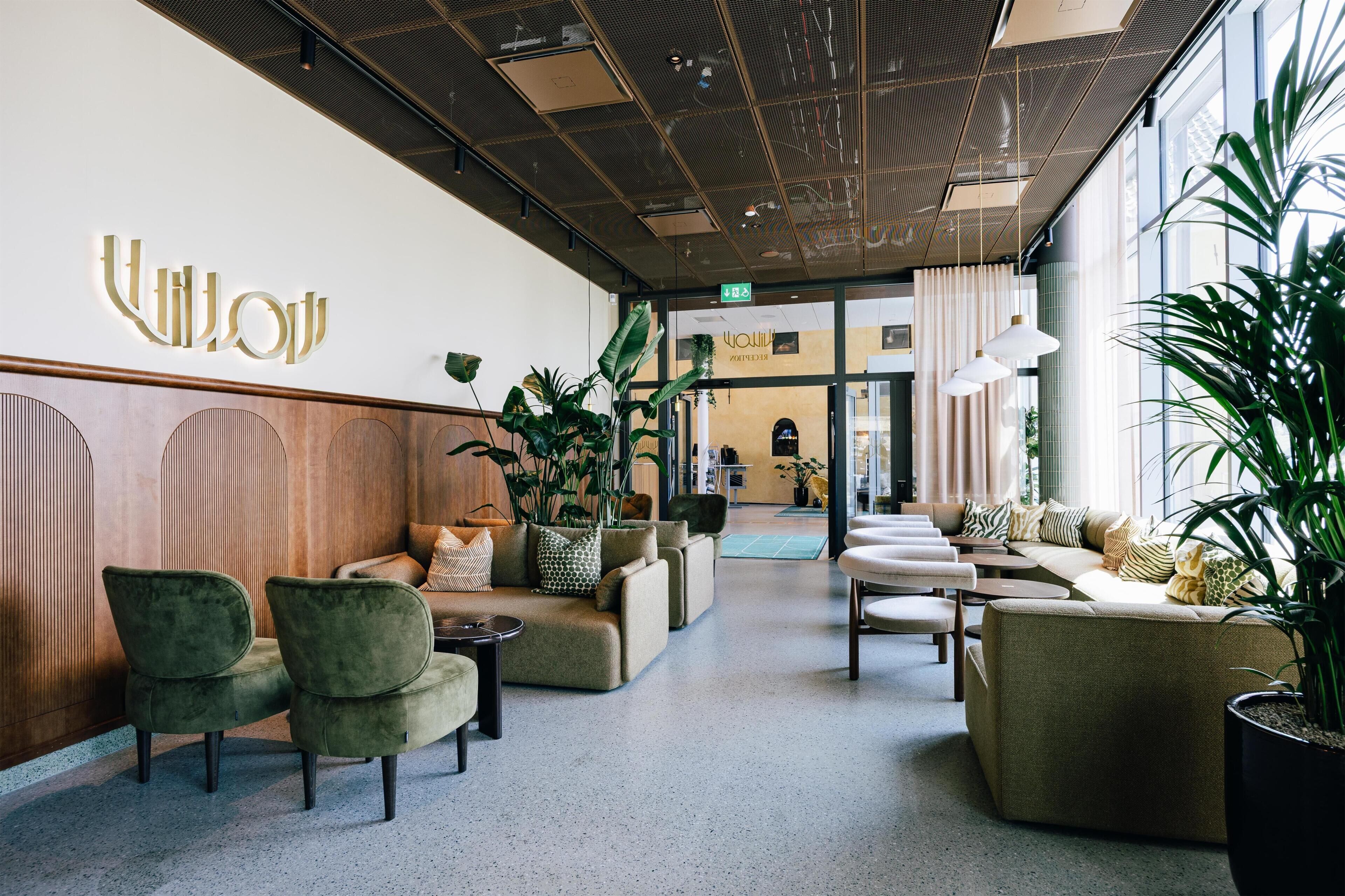 Eine moderne Lobby mit Sitzbereichen, einem Empfangsschalter und einem großen Fenster.