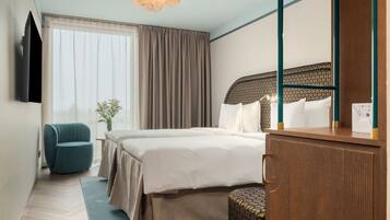 A hotel room with a bed, a desk, a chair, a television, and a window with curtains.