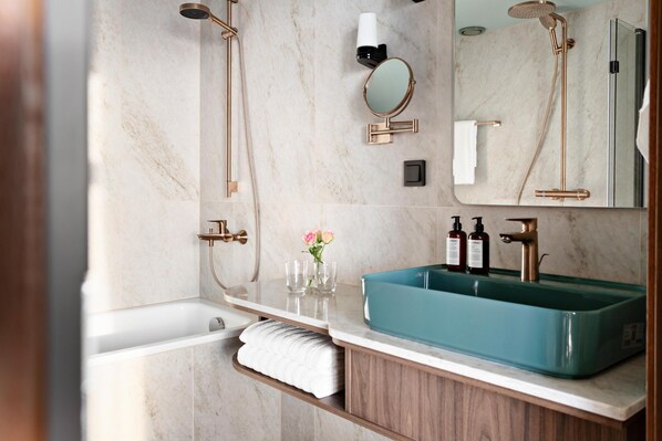 A bathroom with a bathtub, a large mirror, a sink with a faucet, and a showerhead. - Willow, Worldhotels Crafted (Trelleborg)