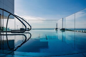 A modern infinity pool with a clear view of the ocean and wind turbines in the distance. - Willow, Worldhotels Crafted (Trelleborg)