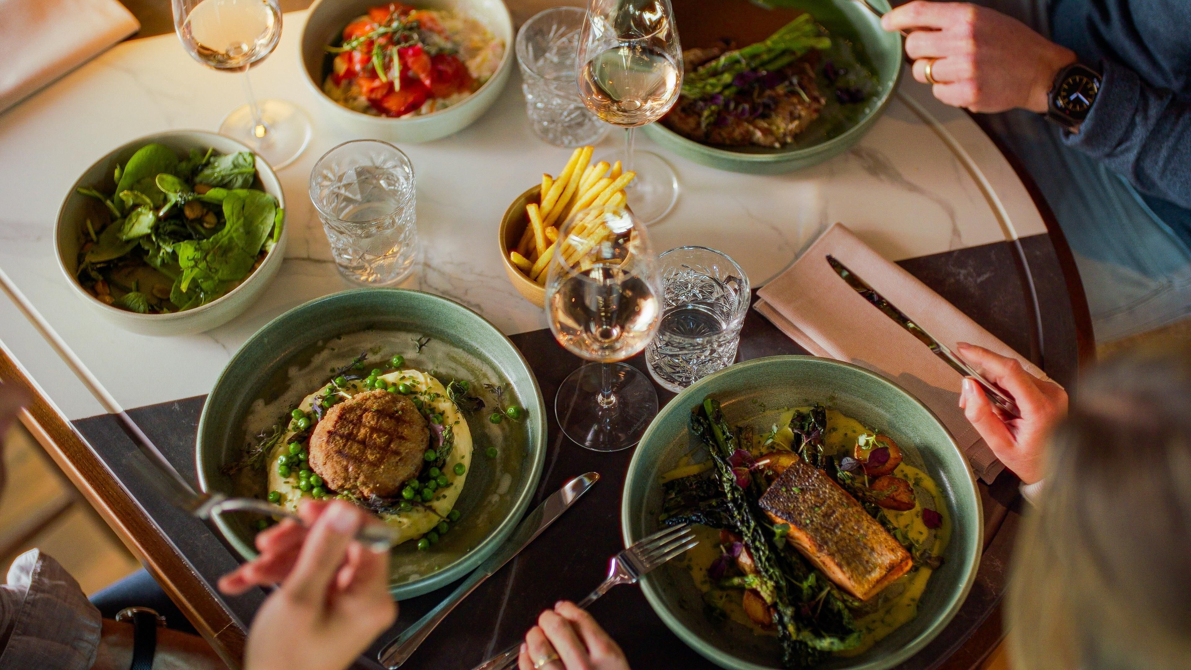 A dining table with various dishes, glasses of water, and cutlery.