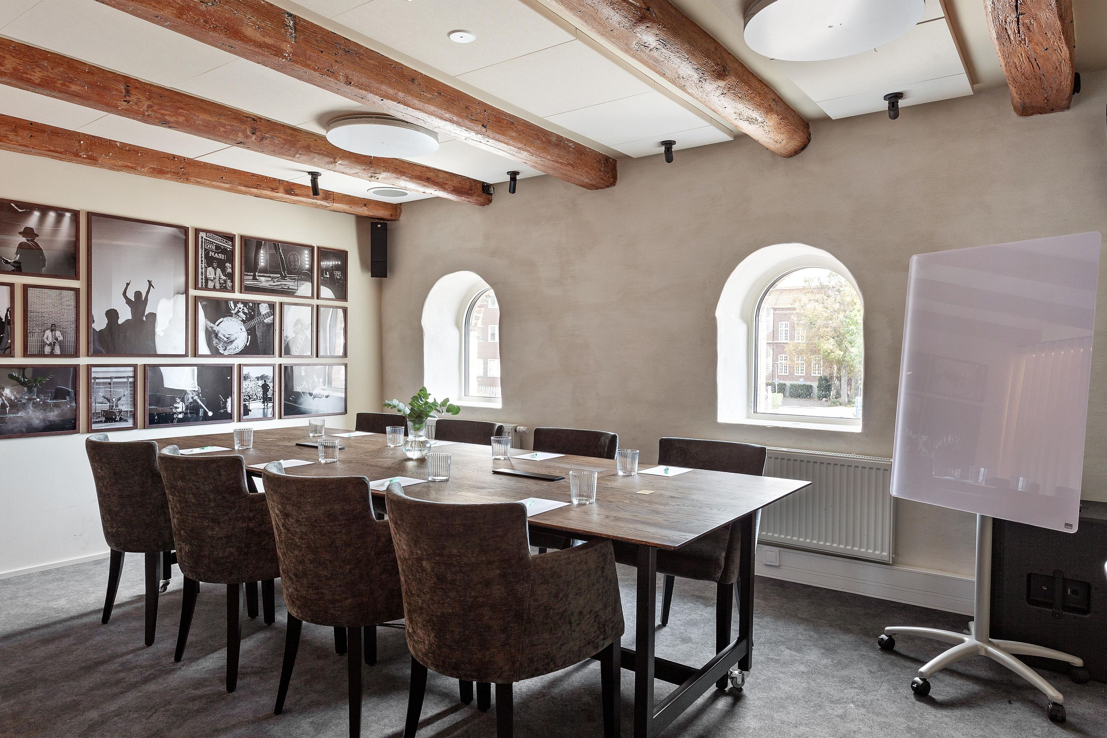 A conference room with a long table, chairs, a whiteboard, and framed pictures on the wall.