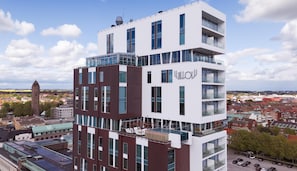 A multi-story building with a modern architectural design, featuring balconies and large windows.