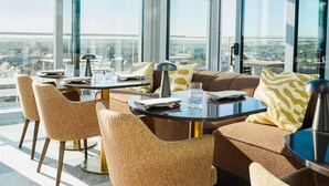 A modern dining area with round tables and cushioned chairs, large windows, and a city view. - Willow, Worldhotels Crafted (Trelleborg)