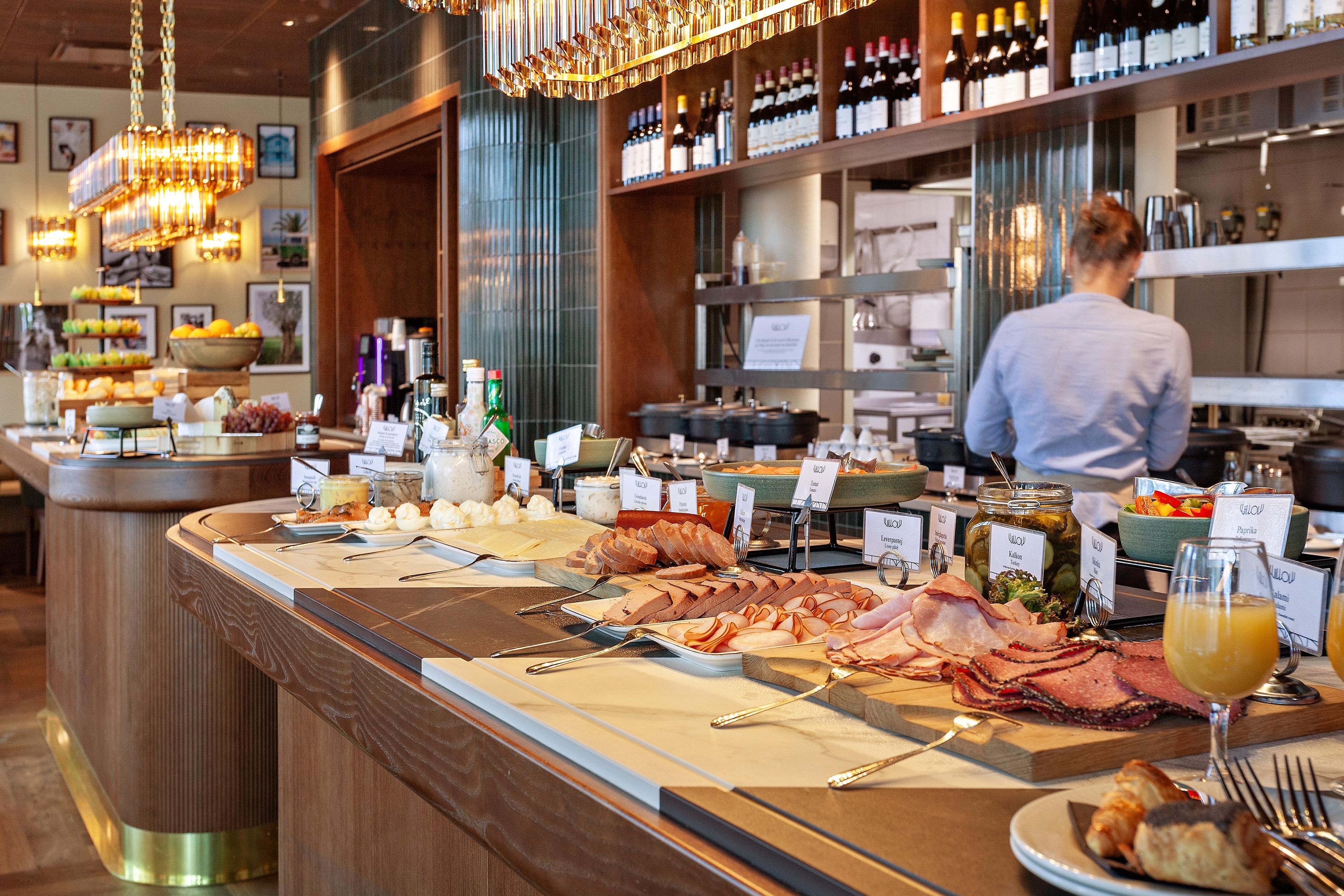 Un bufé con diversos alimentos y un bartender al fondo.