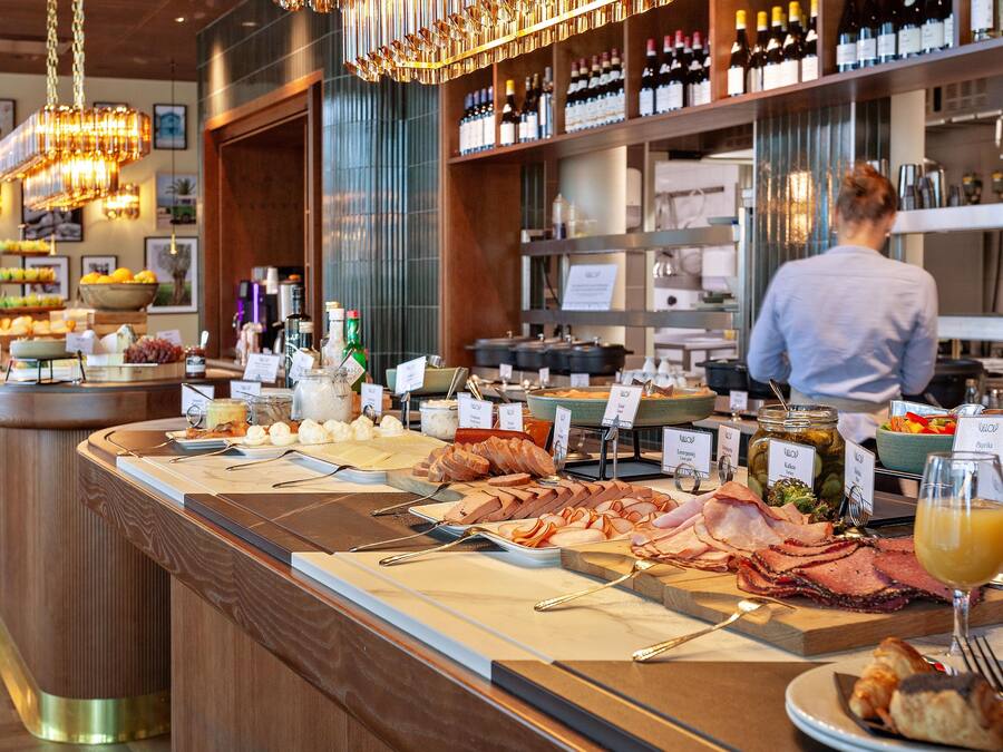 Un bufé con diversos alimentos y un bartender al fondo.