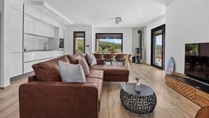A modern living room with a brown leather sofa, a round coffee table, and a TV. - Villa Enja in tranquille village with heated salted pool (Vintijan)