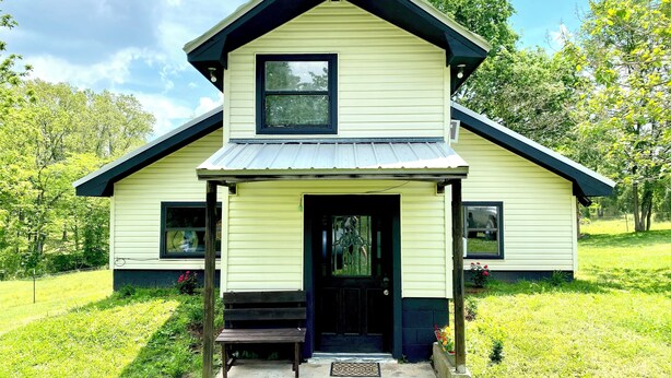 A two-story house with a front porch and a small bench. - Tranquil 2-bedroom house with AC, fire pit, & game room in the Ozarks (Marshall)