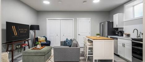 Un appartement moderne comprenant un salon, un coin repas et une cuisine. Il est équipé d’un téléviseur à écran plat, d’un canapé, d’une table à manger et d’une cuisine avec un réfrigérateur et une cuisinière.