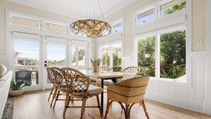 A dining area with a large table, wicker chairs, and a hanging light fixture. - Private Pool | Great for Families | Tides of Joy (Isle of Palms)