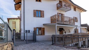 A multi-story building with balconies, a gated entrance, and a paved courtyard. - Casa Del Torchio: Apartment with vineyard view in Trentino (Valternigo)