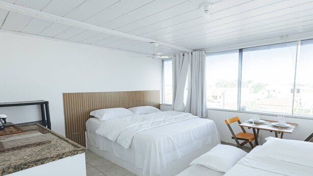 Een hotelkamer met een bed, een kleine tafel met stoelen en een raam met gordijnen.