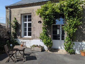 A building with a window, a door, and a table with chairs outside. - "La Bone École" guesthouse - La Récré (Les Landes-Genusson)