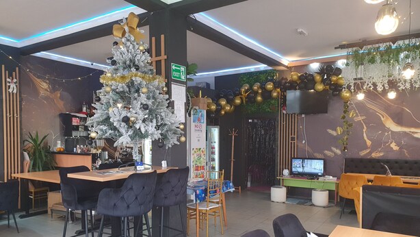 Un intérieur de restaurant moderne, avec un sapin de Noël, un bar et des espaces pour s’asseoir.
