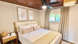 A neatly arranged bedroom with a bed, bedside table, and a window with curtains. - Anchor Cabin | Walk to Lake Como + Fire Pit + Grill (Lake Geneva)