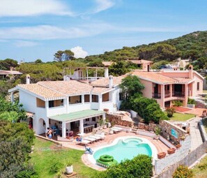 Una villa con piscina, area relax esterna e un giardino rigoglioso.