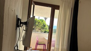 A room with a bed, a desk with a lamp, a chair, and a view of the outdoors. - Seafront villa (Cala Caterina)