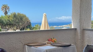 A balcony with a table and chairs, overlooking a coastal view. - Seafront villa (Cala Caterina)