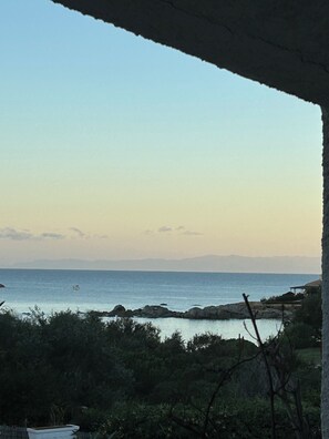 A coastal view with a clear sky, a body of water, and rocky terrain. - Seafront villa (Cala Caterina)