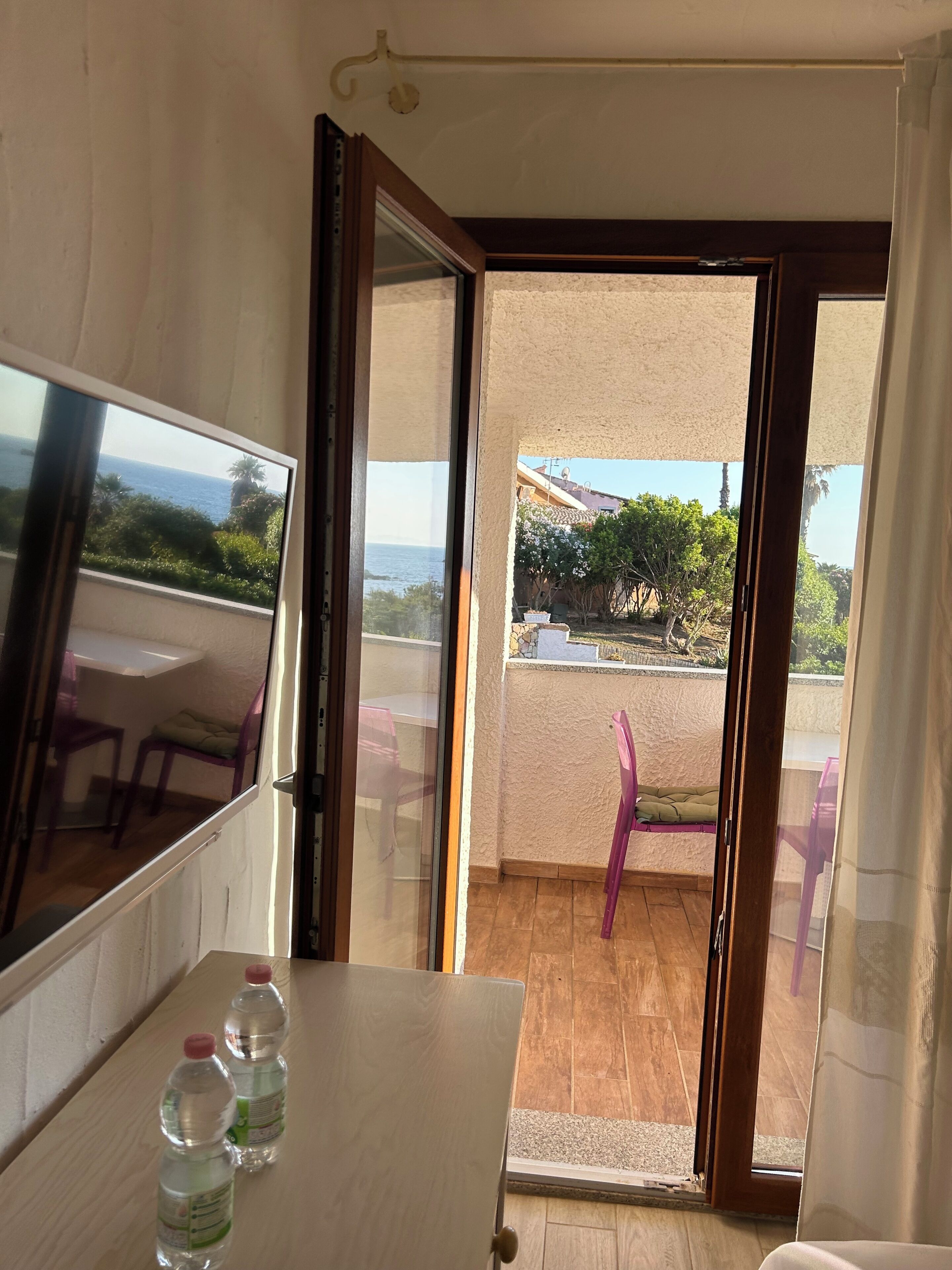 A room with a wooden table, two water bottles, a sliding glass door leading to an outdoor area with a patio and chairs.