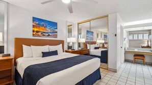 A hotel room with a large bed, a desk, a mirror, and artwork on the walls. - Relax & Explore: Spacious 2BR Suite at Maui Schooner Resort (Kihei)