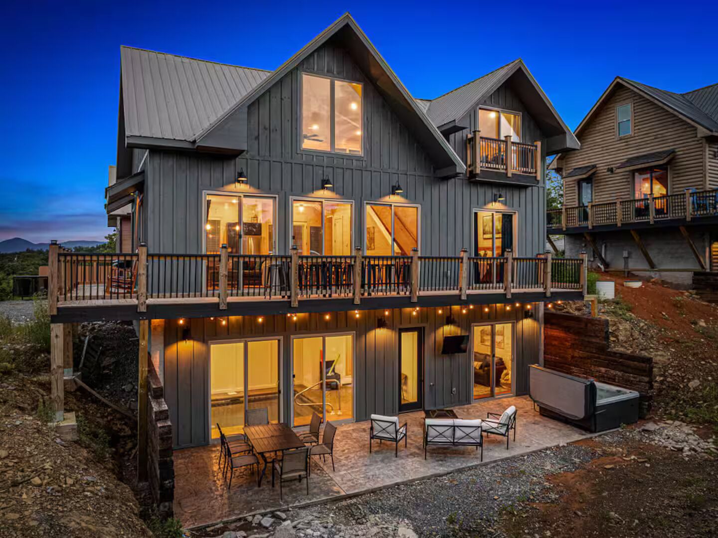 A large, two-story house with a balcony, large windows, and outdoor seating.