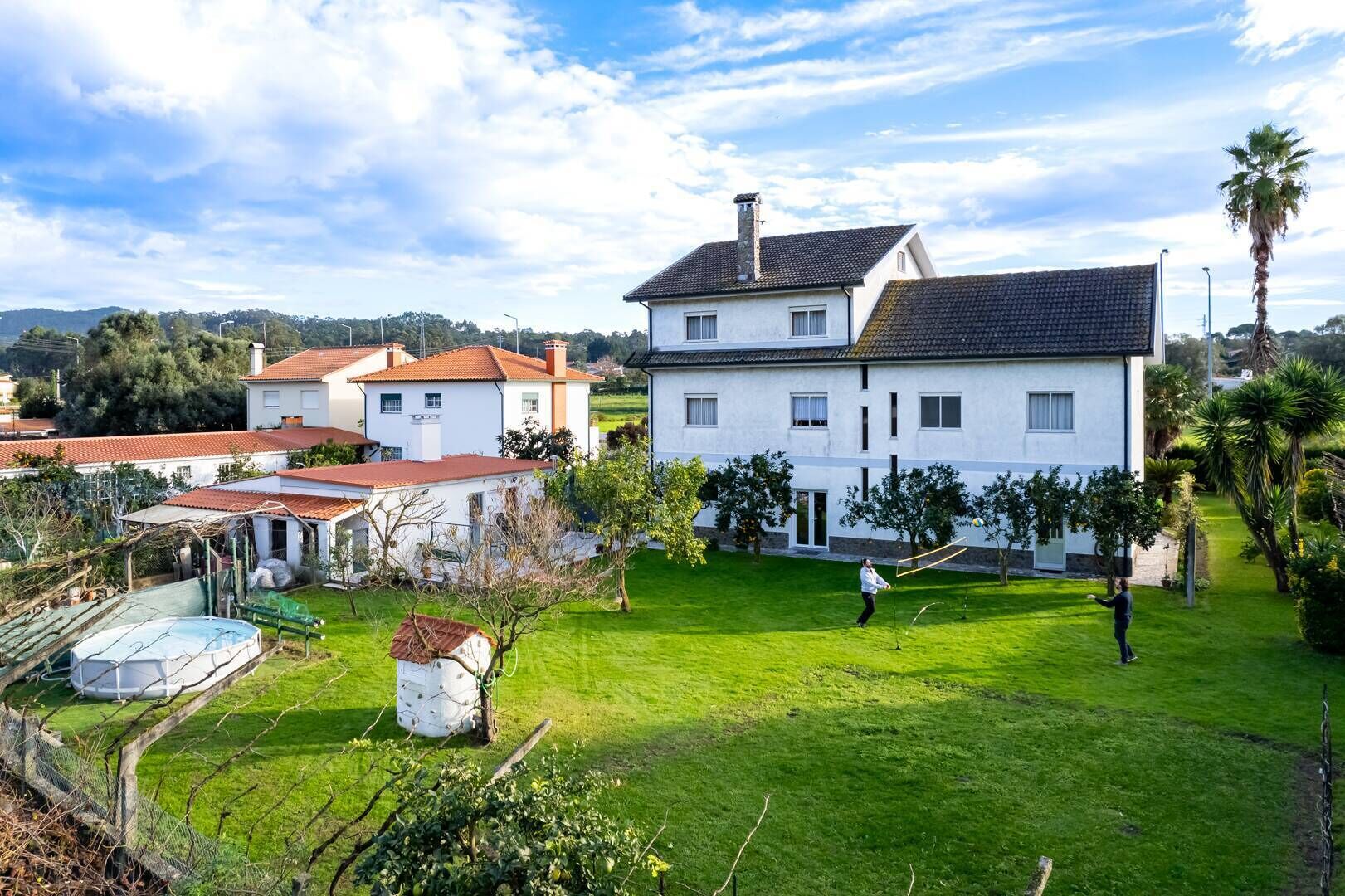 Una casa grande con un césped bien cuidado y una cancha de tenis.