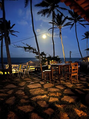 A patio area with a table and chairs, palm trees, and a view of the ocean. - Relax with incredible views, 80 meters from the sea, pet-friendly. (Icapuí)