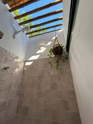 A tiled bathroom with a hanging plant, a shower, and a window with a view of greenery. - Relax with incredible views, 80 meters from the sea, pet-friendly. (Icapuí)