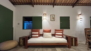Un lit avec une tête de lit et un pied de lit en bois, deux appliques murales, un tableau encadré et une fenêtre donnant sur un paysage.