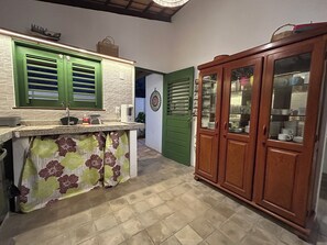 A kitchen with a counter, green cabinets, and a wooden cabinet with glass doors. - Relax with incredible views, 80 meters from the sea, pet-friendly. (Icapuí)
