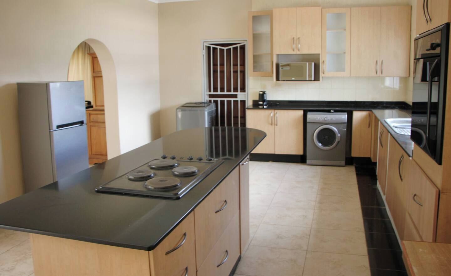 A kitchen with a central island, stainless steel appliances, and wooden cabinets.