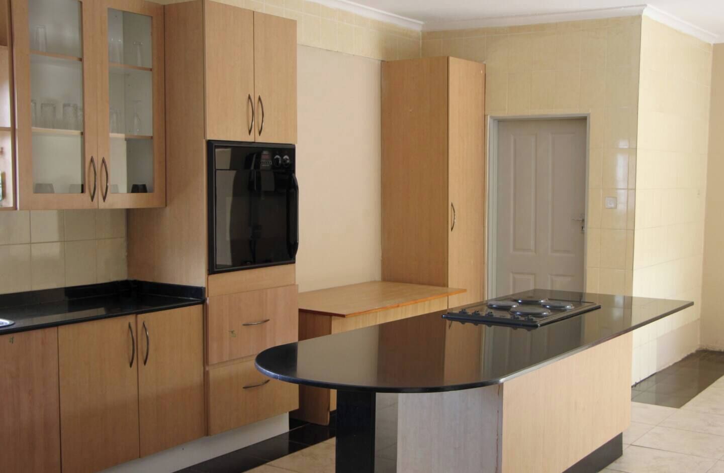A kitchen with wooden cabinets, a black countertop, and a built-in oven.