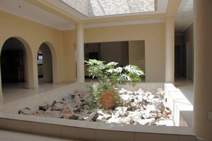 A spacious atrium with a central rock garden and a potted plant. - Lovely 7-bedroom house in Harare perfect for group stays, hosts up to 20 guests. (Harare)