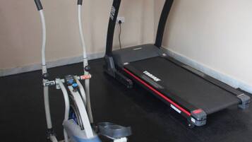 A treadmill and an elliptical machine in a room with a black floor and beige walls.