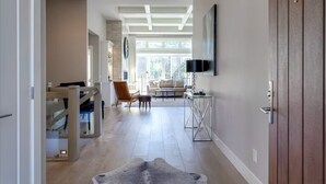 A modern interior with a wooden staircase, a living area with a sofa and TV, and a dining area with a table and chairs.