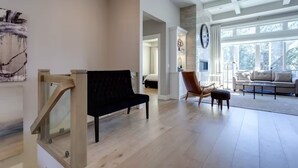 A spacious living room with a wooden bench, a sofa, and a coffee table. There is a large window providing natural light and a view of the outdoors.