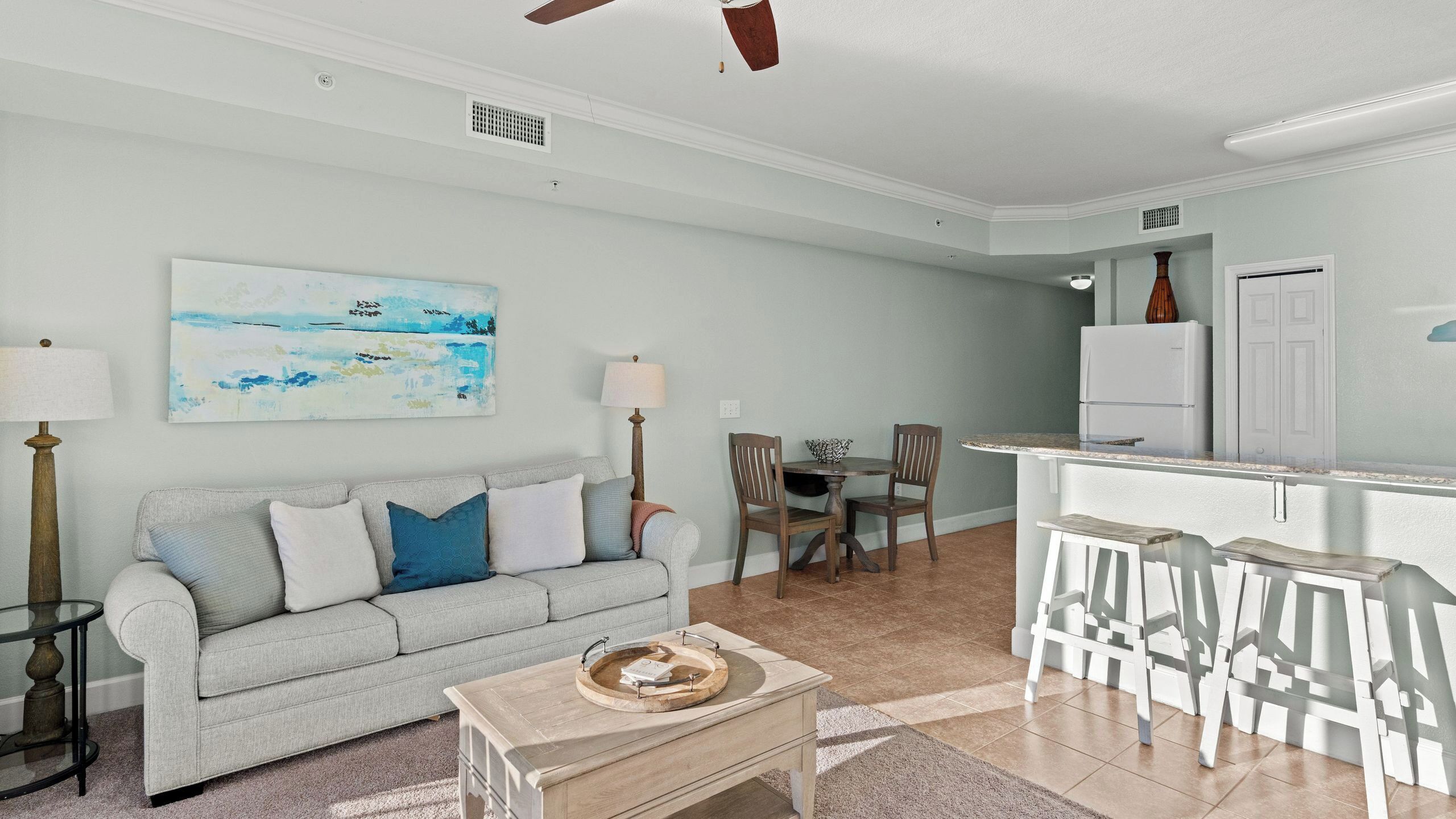 A living room with a sofa, coffee table, and a painting on the wall.
