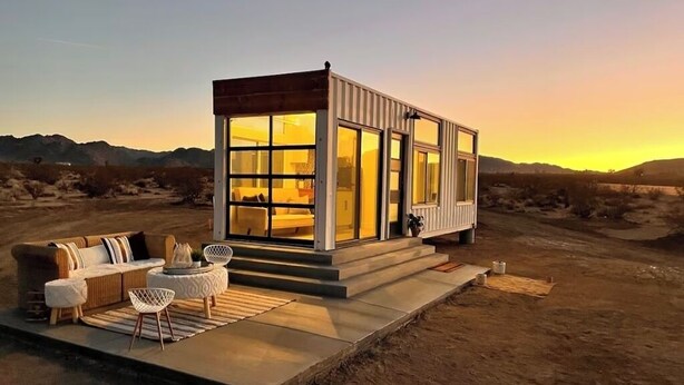 Un edificio moderno e compatto con ampie finestre, un tetto piatto e una terrazza con mobili da esterno.
