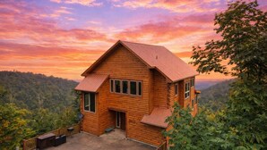 Eine Holzhütte mit geneigtem Dach, einer Veranda und Blick auf ein bewaldetes Tal.