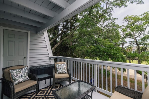 Un porche con barandal blanco, una puerta y un espacio de estar con mesa y sillas.