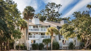 A multi-story building with balconies, surrounded by trees and a well-maintained lawn. - 253 Driftwood:Beautiful 2nd Floor Villa;Golf Course Views;Dogs Welcome (Edisto Beach)