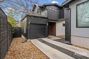 Ein modernes, zweistöckiges Haus mit Garage, überdachter Terrasse und einem kleinen Garten.